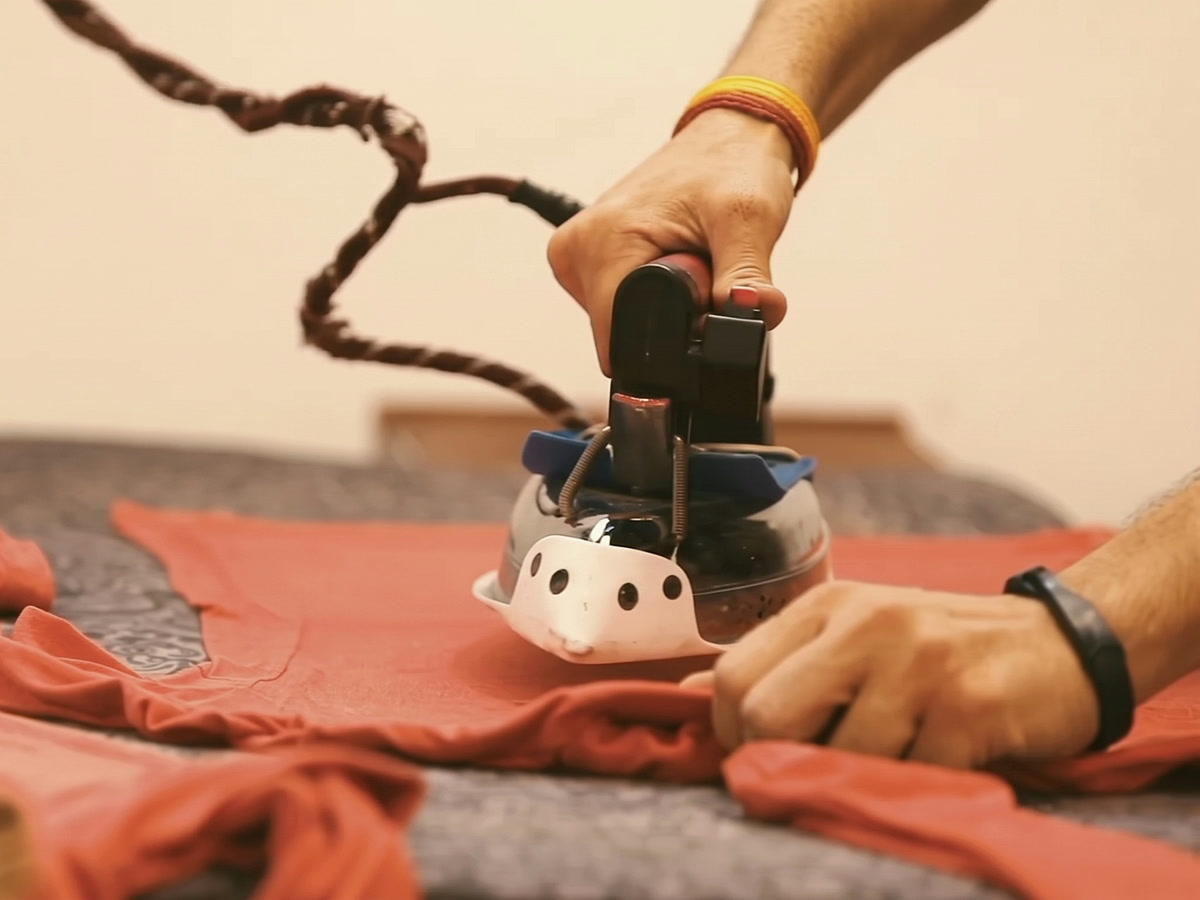 Hands pressing a knitted garment laid flat on a table